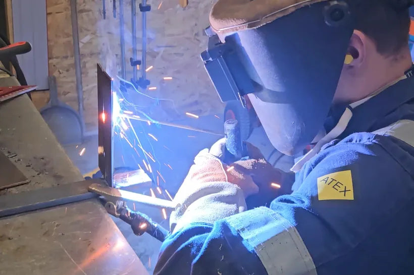 Alexis soude une équerre dans son atelier, étincelles