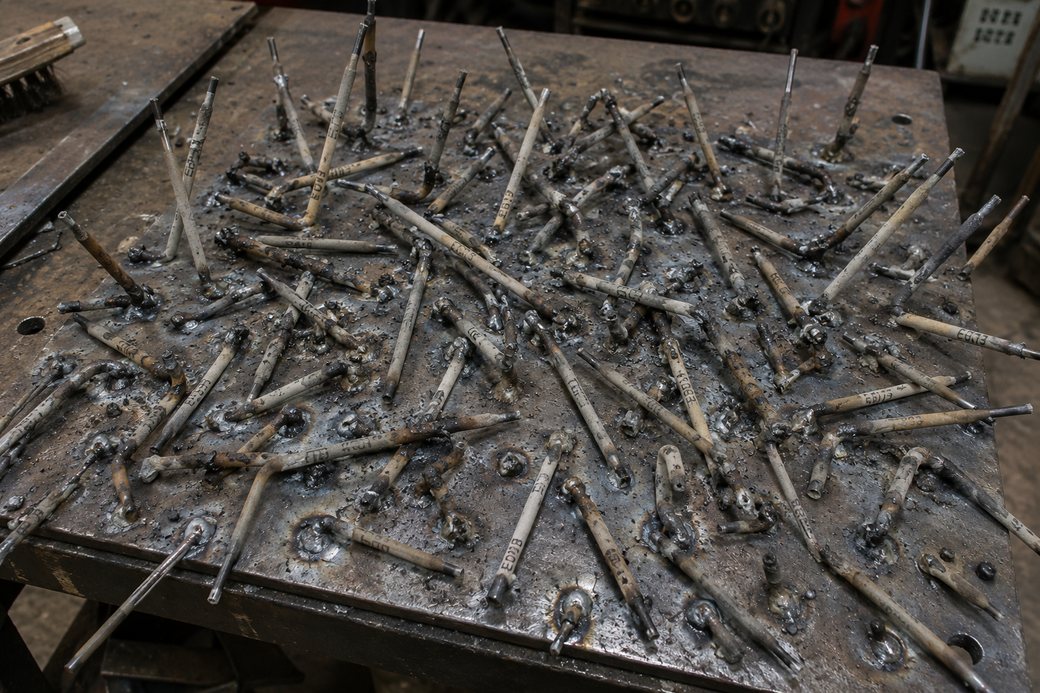 Plaque d'acier couverte de dizaines de baguettes collées et cramées, le rebut de séances d'amorçage ratées